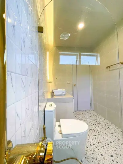 Modern bathroom with elegant fixtures and terrazzo flooring, featuring a sleek shower and stylish vanity.