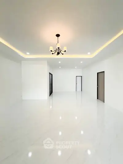Spacious modern living room with elegant chandelier and sleek white flooring.