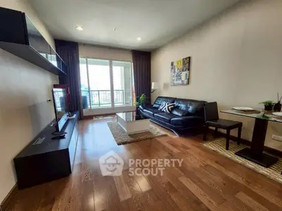 Modern living room with sleek furniture and hardwood floors, featuring a large window with balcony access.