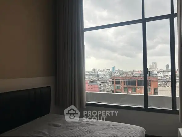 Cozy bedroom with city view through large window, perfect urban living.