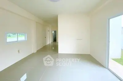 Spacious empty room with glossy tiled flooring and natural light