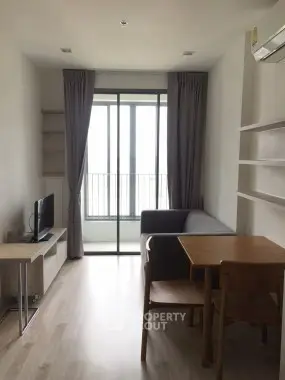 Modern living room with sleek furniture and large window offering natural light.