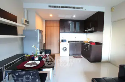 Modern kitchen with sleek cabinets, dining area, and built-in appliances in a stylish apartment.