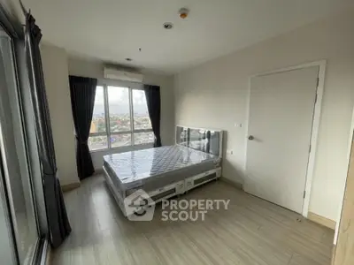 Modern bedroom with large window and city view in high-rise apartment