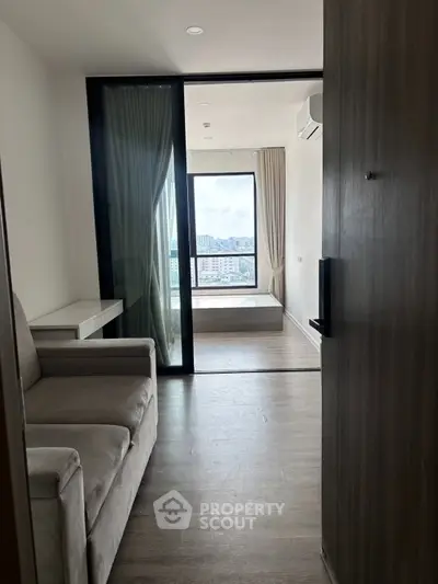 Modern apartment interior with a cozy living area and a bedroom with a stunning city view.