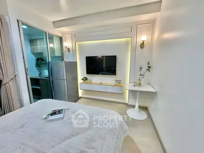 Modern bedroom with sleek TV setup and cozy lighting in stylish apartment.