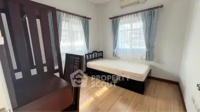 Cozy bedroom with wooden furniture and natural light, perfect for relaxation.