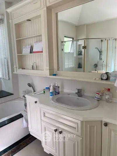 Elegant bathroom with classic white cabinetry and modern fixtures, featuring a bathtub and spacious vanity area.