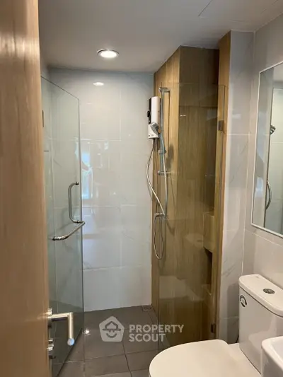 Modern bathroom with glass shower and sleek fixtures in contemporary apartment.