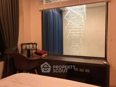 Cozy bedroom with modern decor and large window showcasing elegant chandelier view.