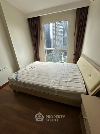 Cozy bedroom with city view, featuring a comfortable bed and large window for natural light.