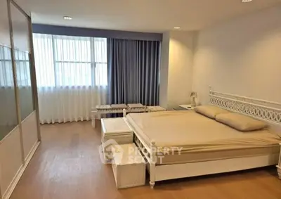 Spacious bedroom with elegant decor and large window for natural light.