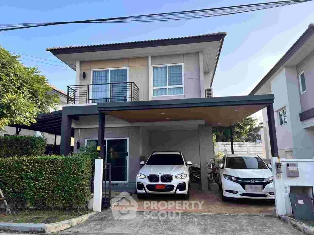 Modern two-story house with carport and two cars parked in driveway