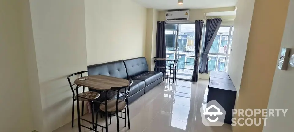 Modern living room with sleek black sofa and dining set, bright natural light from large windows.