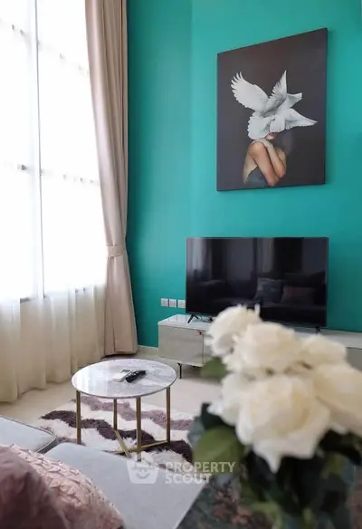 Stylish living room with teal accent wall, modern TV setup, and elegant decor.