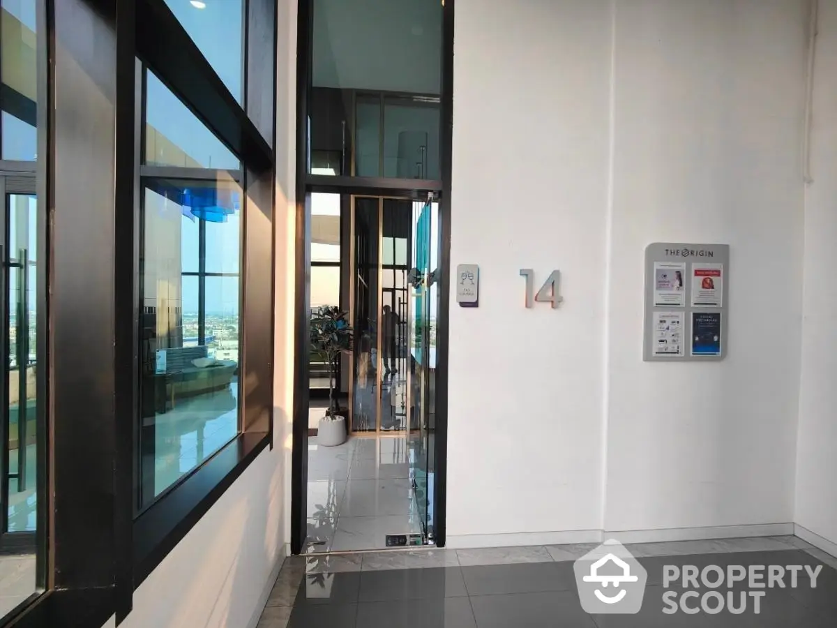 Modern building entrance with glass doors and city view, high floor access.