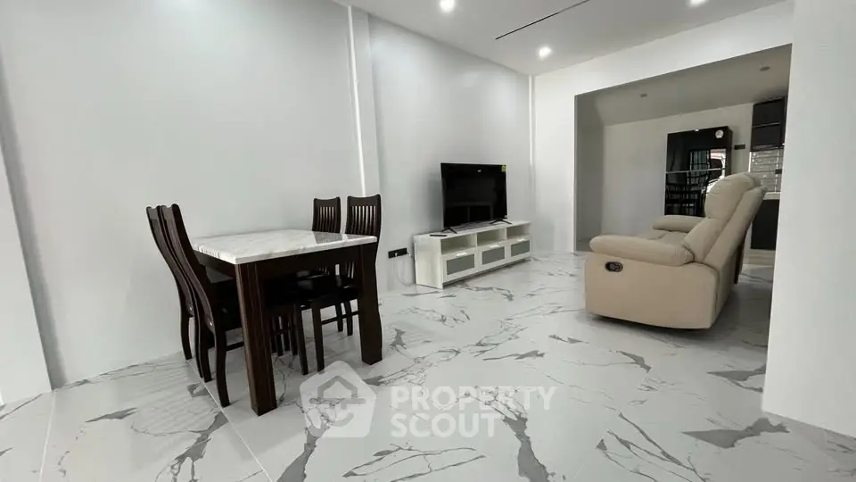 Modern living room with marble flooring, dining set, and cozy seating area.