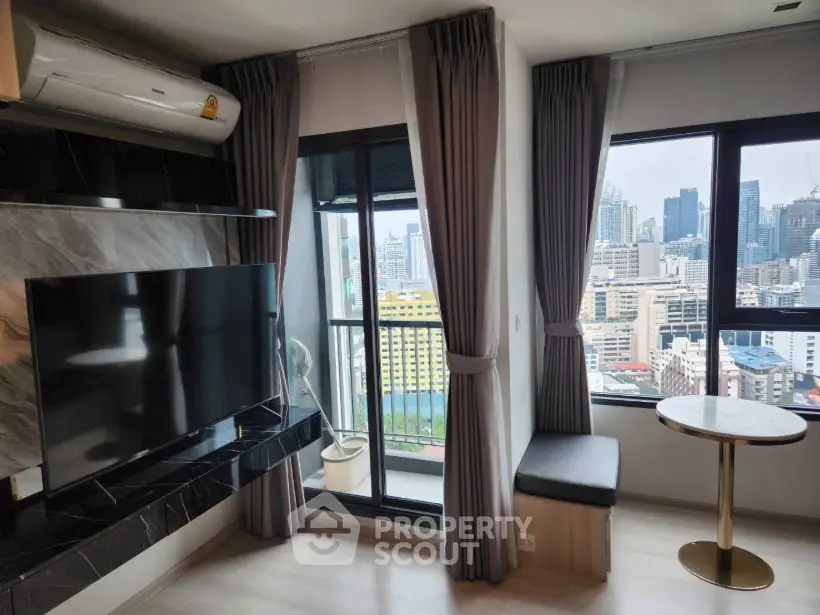 Modern living room with city view, featuring large windows, sleek TV setup, and stylish decor.
