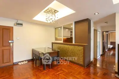Elegant dining area with modern lighting and wooden flooring in open layout apartment.