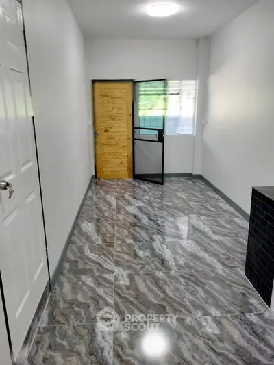 Spacious hallway with modern tile flooring and wooden door
