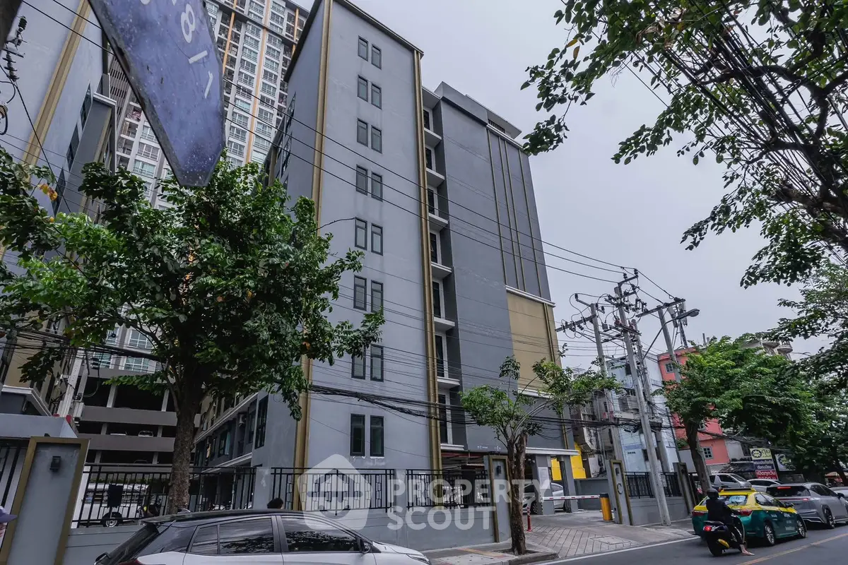 Modern urban apartment building with street view and lush greenery.
