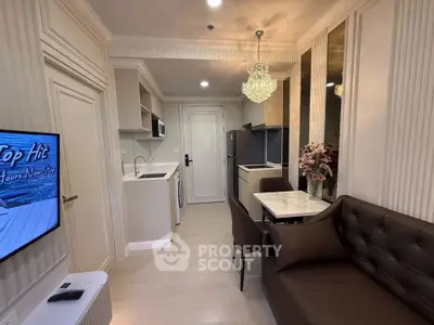 Modern living room with elegant chandelier and sleek kitchen in open layout apartment.