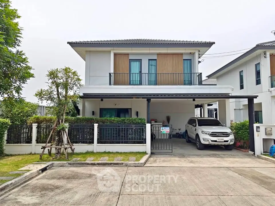 Modern two-story house with carport and landscaped garden in suburban neighborhood.