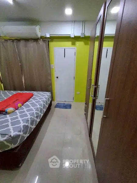 Cozy bedroom with mirrored wardrobe and vibrant yellow accent wall