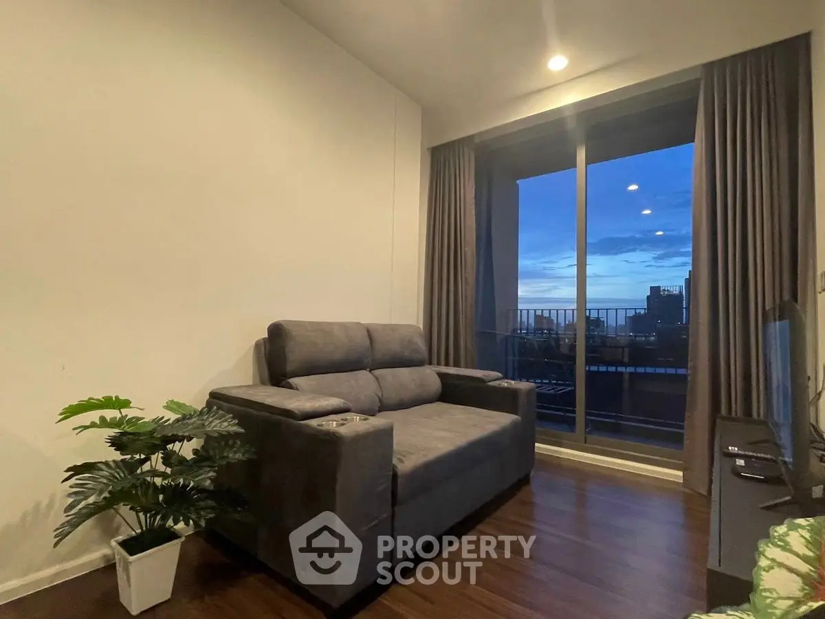 Cozy living room with plush sofa and stunning city view from balcony at dusk.
