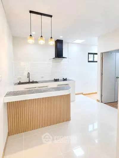 Modern kitchen with sleek design, featuring a gas stove and stylish lighting fixtures.
