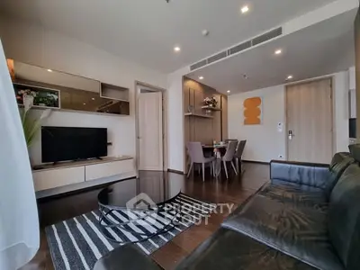 Modern living room with sleek furniture and dining area, featuring stylish decor and ample natural light.