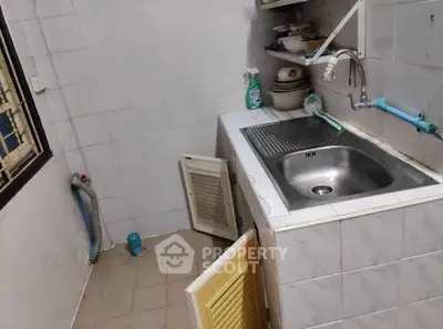 Compact kitchen with sink and storage in a tiled room