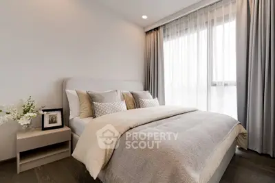 Elegant bedroom with modern decor and large window offering natural light.