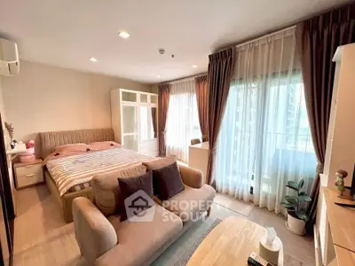 Spacious bedroom with cozy seating area and large windows opening to a balcony.