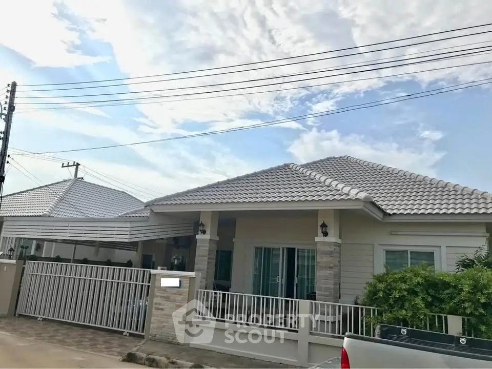 Charming single-story house with tiled roof and gated entrance in a serene neighborhood.
