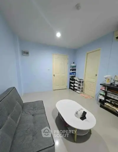 Cozy living room with modern gray sofa and stylish white coffee table in a bright blue-walled interior.