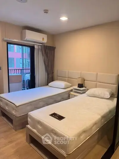 Cozy twin bedroom with modern decor and balcony access in urban apartment.