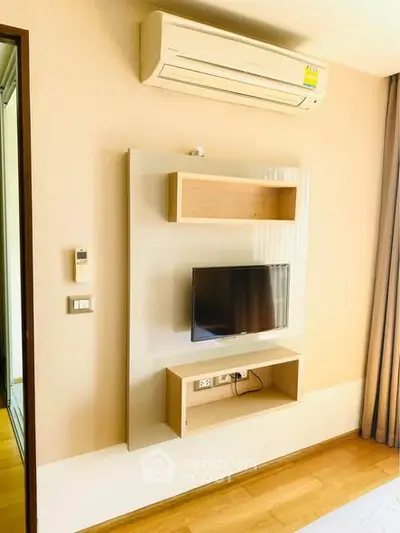 Modern living room with wall-mounted TV and air conditioning unit, featuring sleek wooden flooring.