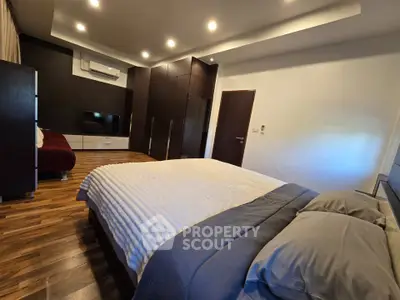 Spacious modern bedroom with elegant wooden flooring and cozy lighting