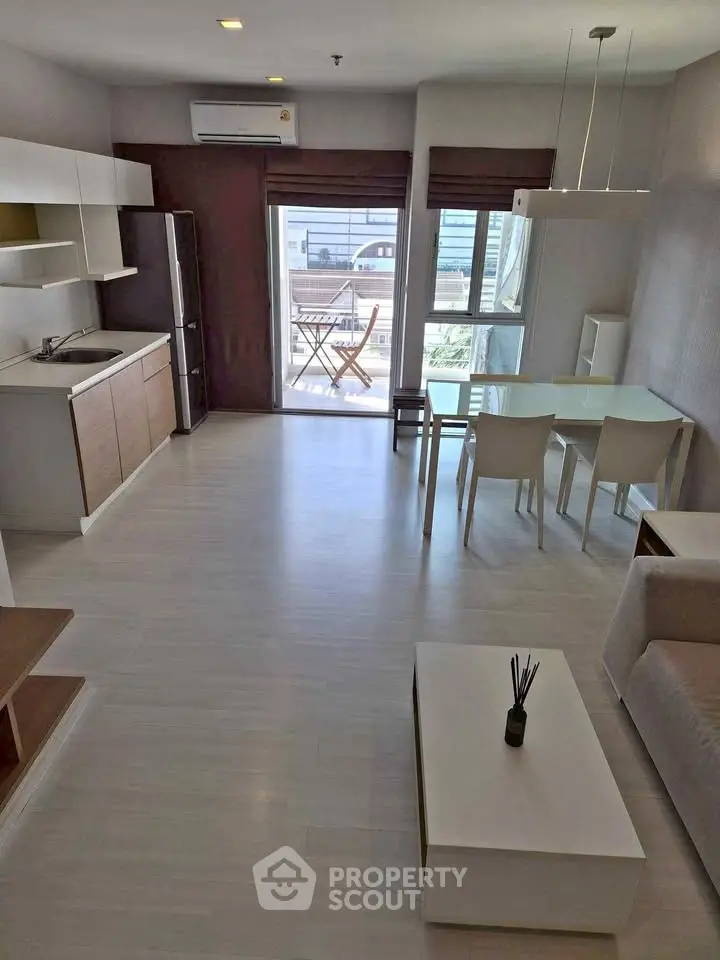 Modern open-plan living room with dining area and balcony access in a stylish apartment.