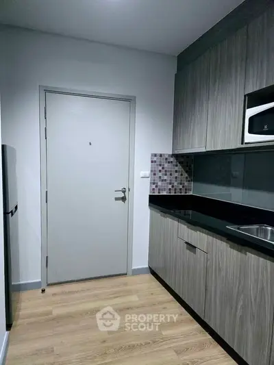 Modern kitchen with sleek cabinetry and wood flooring in a compact layout.