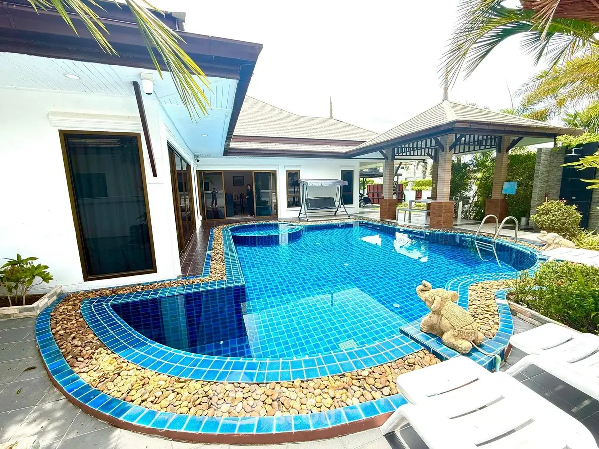 Luxurious villa with stunning blue-tiled pool and elegant outdoor seating area.