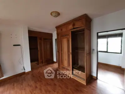 Spacious bedroom with wooden flooring and built-in wardrobes, perfect for cozy living.
