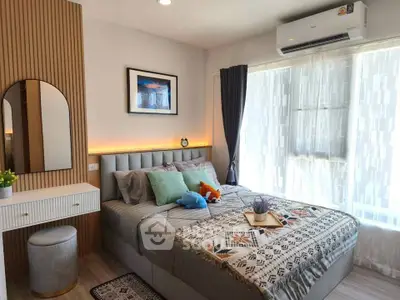 Cozy bedroom with modern decor, large window, and stylish furnishings in a bright apartment.