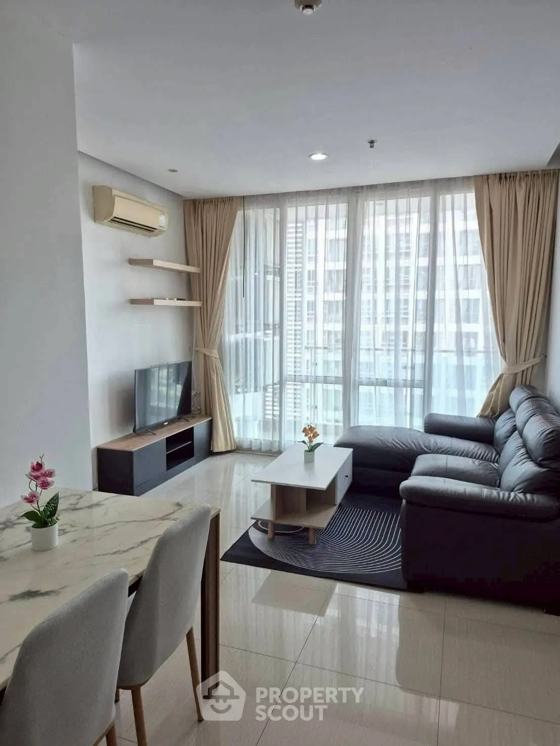 Modern living room with large windows, stylish furniture, and natural light in a high-rise apartment.