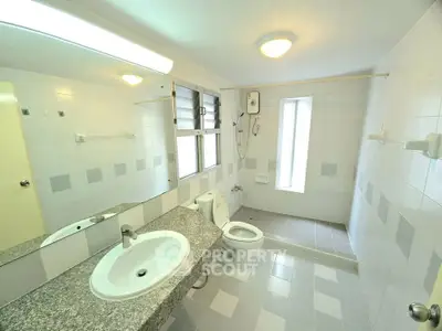 Spacious bathroom with modern fixtures and large mirror in bright apartment.