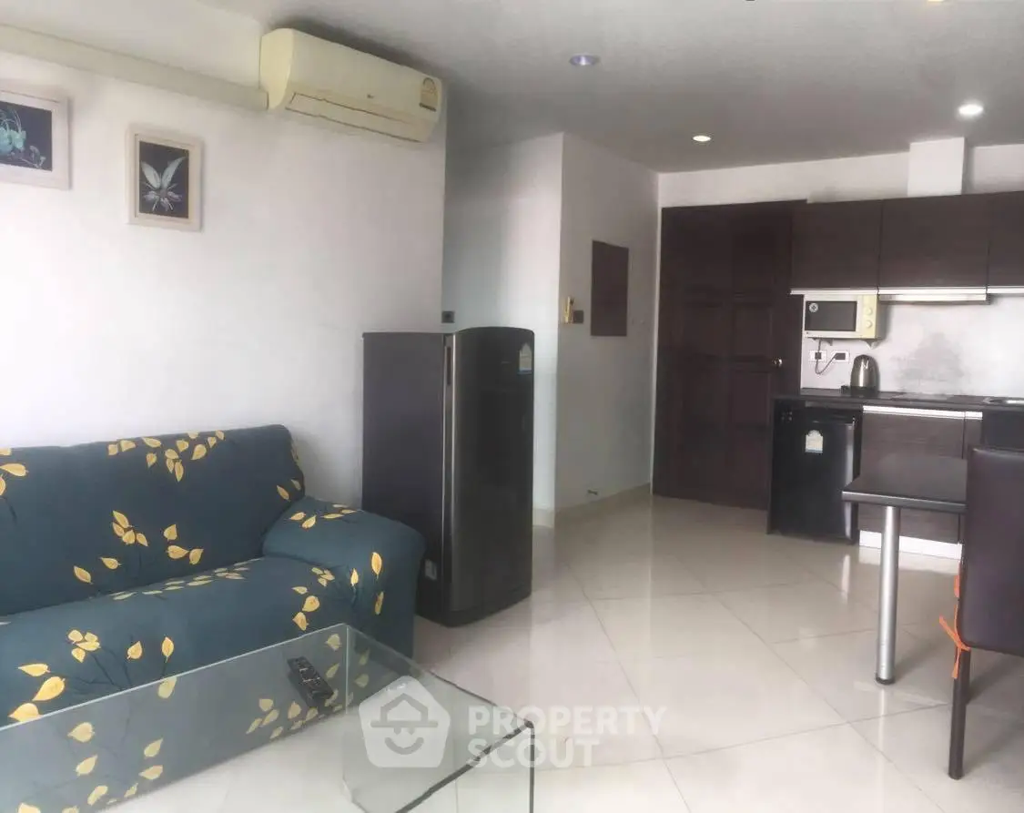 Modern living room with open kitchen, featuring sleek furniture and air conditioning.