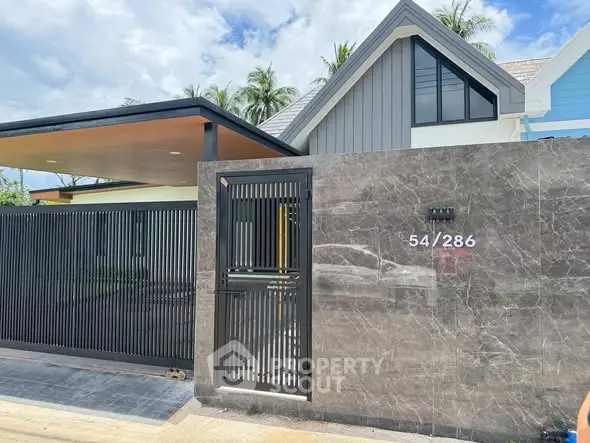 Modern house exterior with sleek gate and stylish facade in tropical setting.