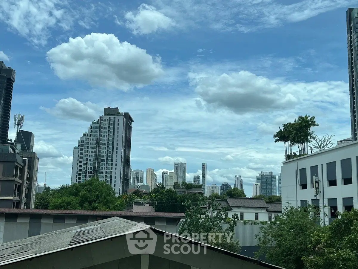 Stunning cityscape view with modern high-rise buildings and lush greenery under a vibrant blue sky.
