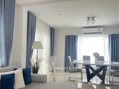 Elegant living room with modern dining area, featuring stylish blue curtains and chic decor.